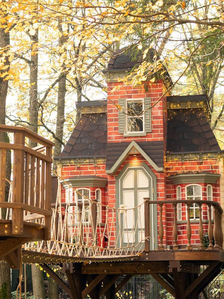 Дом на дереве с кирпичной облицовкой и балконом среди осенней листвы